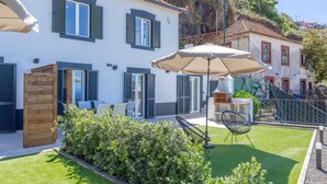 A residential property with a patio area, outdoor seating, and a well-maintained lawn. - Maison Des Souvenir B by YOUR KEY (Ribeira Brava)