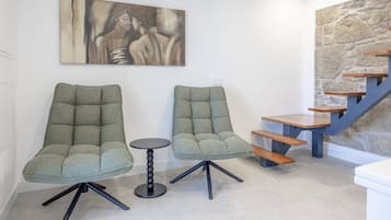 Ein modernes Interieur mit zwei gepolsterten Sessel, einem kleinen runden Tisch und einer Treppe mit Holzstufen.