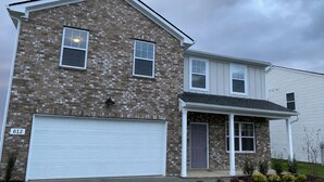 A two-story residential building with a brick facade, a white garage door, and a front porch. - Near Shelbyville, TN. Perfect for long term stays (Murfreesboro)