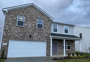 A two-story residential building with a brick facade, a white garage door, and a front porch. - Near Shelbyville, TN. Perfect for long term stays (Murfreesboro)