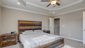 A bedroom with a wooden bed frame, a nightstand, a ceiling fan, and a door leading to another room. - Near Shelbyville, TN. Perfect for long term stays (Murfreesboro)