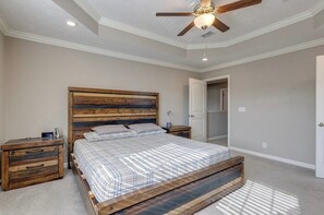 A bedroom with a wooden bed frame, a nightstand, a ceiling fan, and a door leading to another room. - Near Shelbyville, TN. Perfect for long term stays (Murfreesboro)