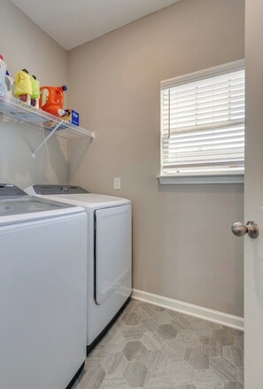 A laundry room with a washing machine, dryer, and shelves with cleaning supplies. - Near Shelbyville, TN. Perfect for long term stays (Murfreesboro)