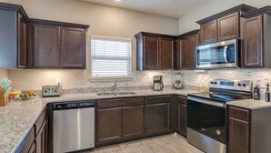 A kitchen with dark wood cabinets, stainless steel appliances, a dishwasher, and a microwave. - Near Shelbyville, TN. Perfect for long term stays (Murfreesboro)