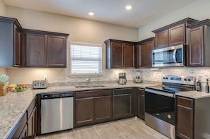 A kitchen with dark wood cabinets, stainless steel appliances, a dishwasher, and a microwave. - Near Shelbyville, TN. Perfect for long term stays (Murfreesboro)