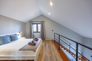 Un dormitorio con cama, almohadas, una ventana y una escalera.