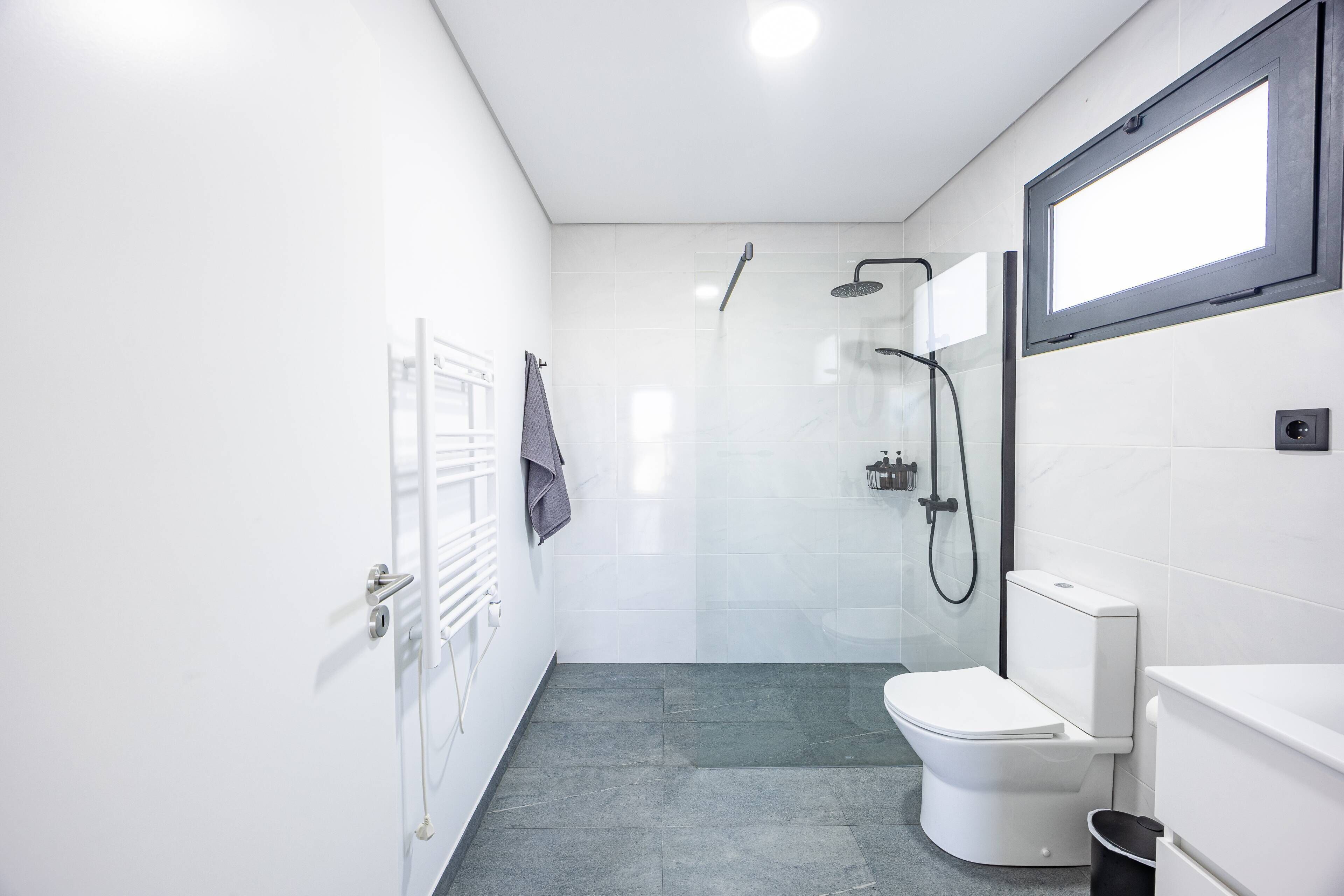 Un baño moderno con inodoro, ducha y toallero.