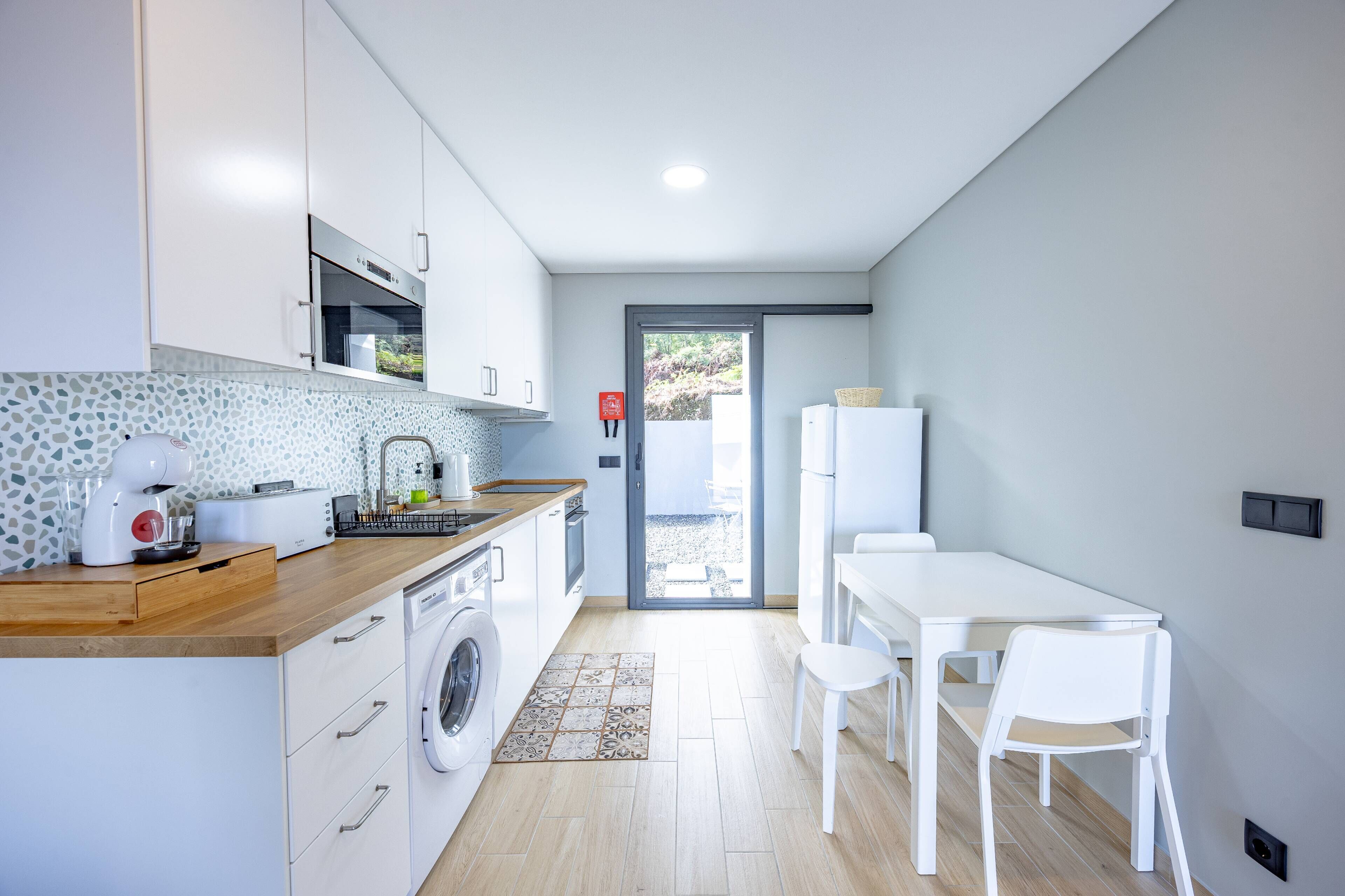 A compact kitchen with a washing machine, a toaster, and a refrigerator.
