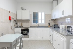 A compact kitchen with white cabinets, a built-in oven, a microwave, and a sink. - Tony's House A by YOUR KEY (Santana)
