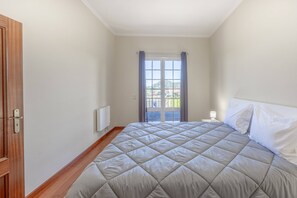A bedroom with a bed, a window with curtains, a radiator, and a door. - Tony's House A by YOUR KEY (Santana)