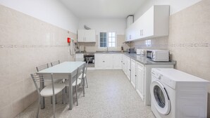 Cocina compacta con comedor, lavadora y ventana que proporciona luz natural.