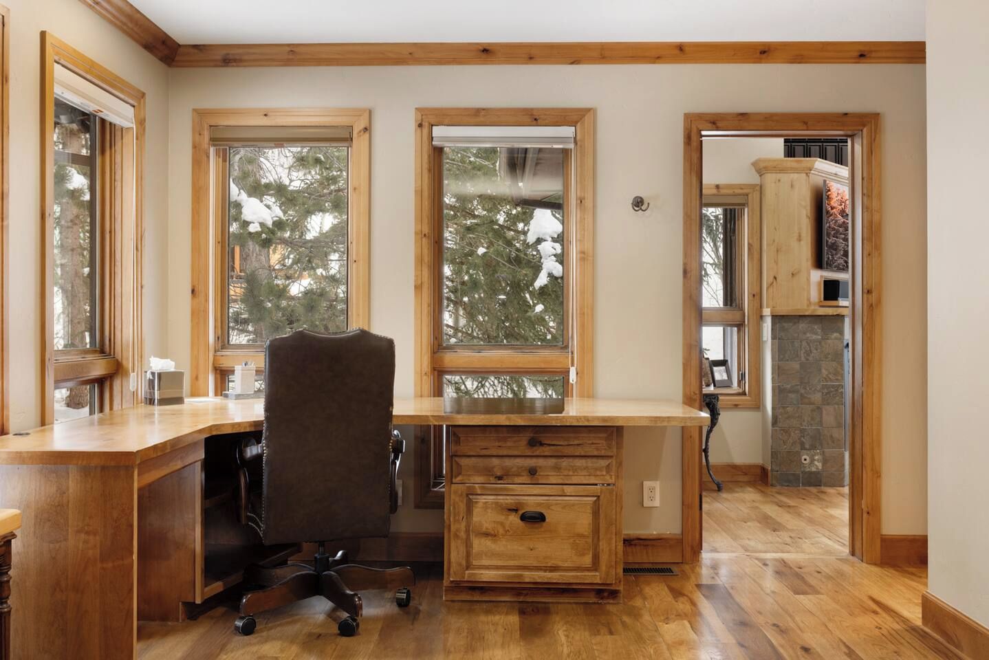 A room with a wooden desk, a chair, and a stone fireplace.