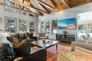 A spacious living room with a large TV, leather sofas, and a wooden ceiling. - Elevated Eagle-Vail Duplex with Hot Tub (Avon)