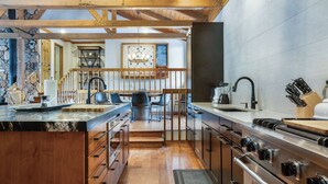 Cozinha moderna com ilha central, eletrodomésticos de aço inoxidável e teto de madeira.