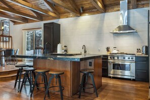 A modern kitchen with a large island, stainless steel appliances, and wooden accents. - Elevated Eagle-Vail Duplex with Hot Tub (Avon)