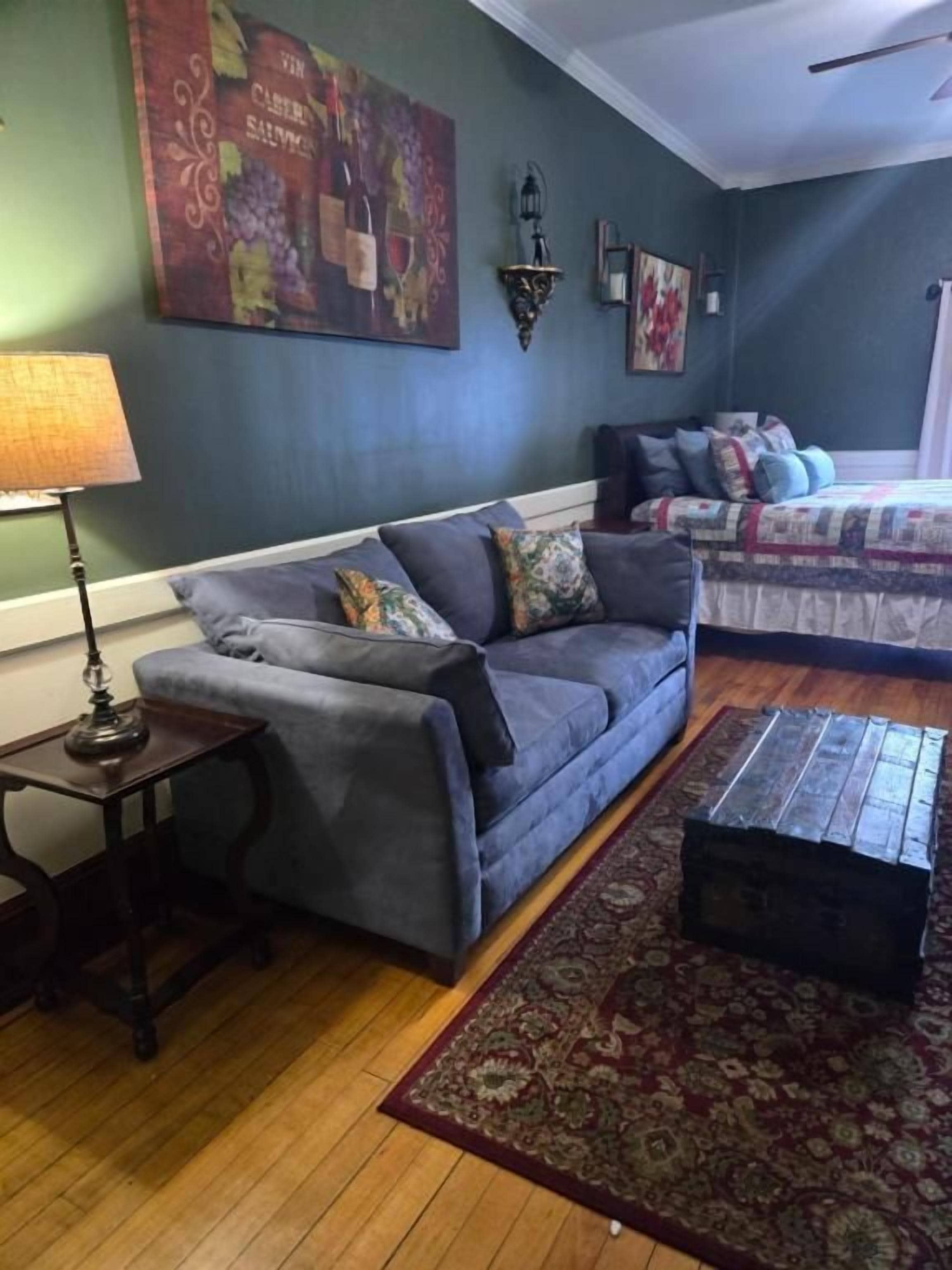 Una habitación con un sofá, una mesita, una alfombra y una cama con edredón estampado.