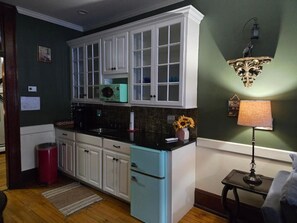 A kitchen with white cabinets, a black countertop, and a teal refrigerator.