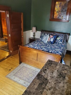 Un dormitorio con una cama de madera, una mesita de noche, una lámpara y una alfombra.