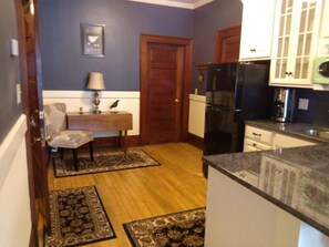 A compact kitchen with a refrigerator, stove, and cabinets. There is a small dining area with a table and chairs. - The Firehouse  (Barre)