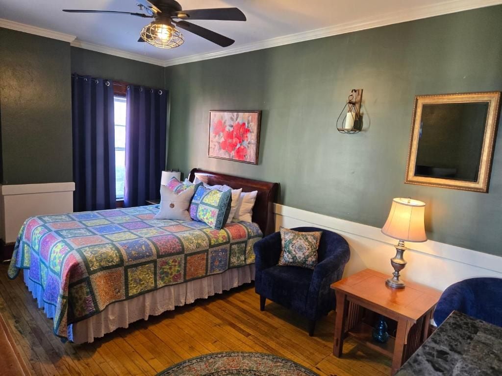A bedroom with a bed, a chair, a lamp, and a ceiling fan.