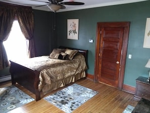 A bedroom with a bed, a wooden door, and a ceiling fan.