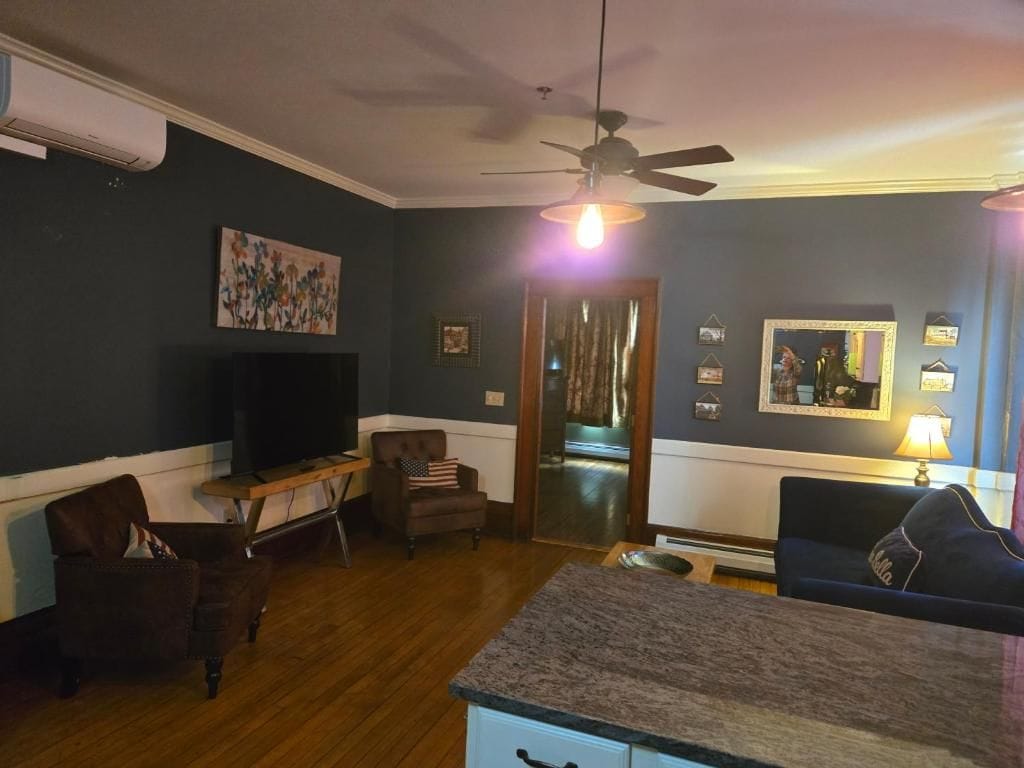Una sala de estar con televisor, ventilador de techo y comedor con mesa y sillas.