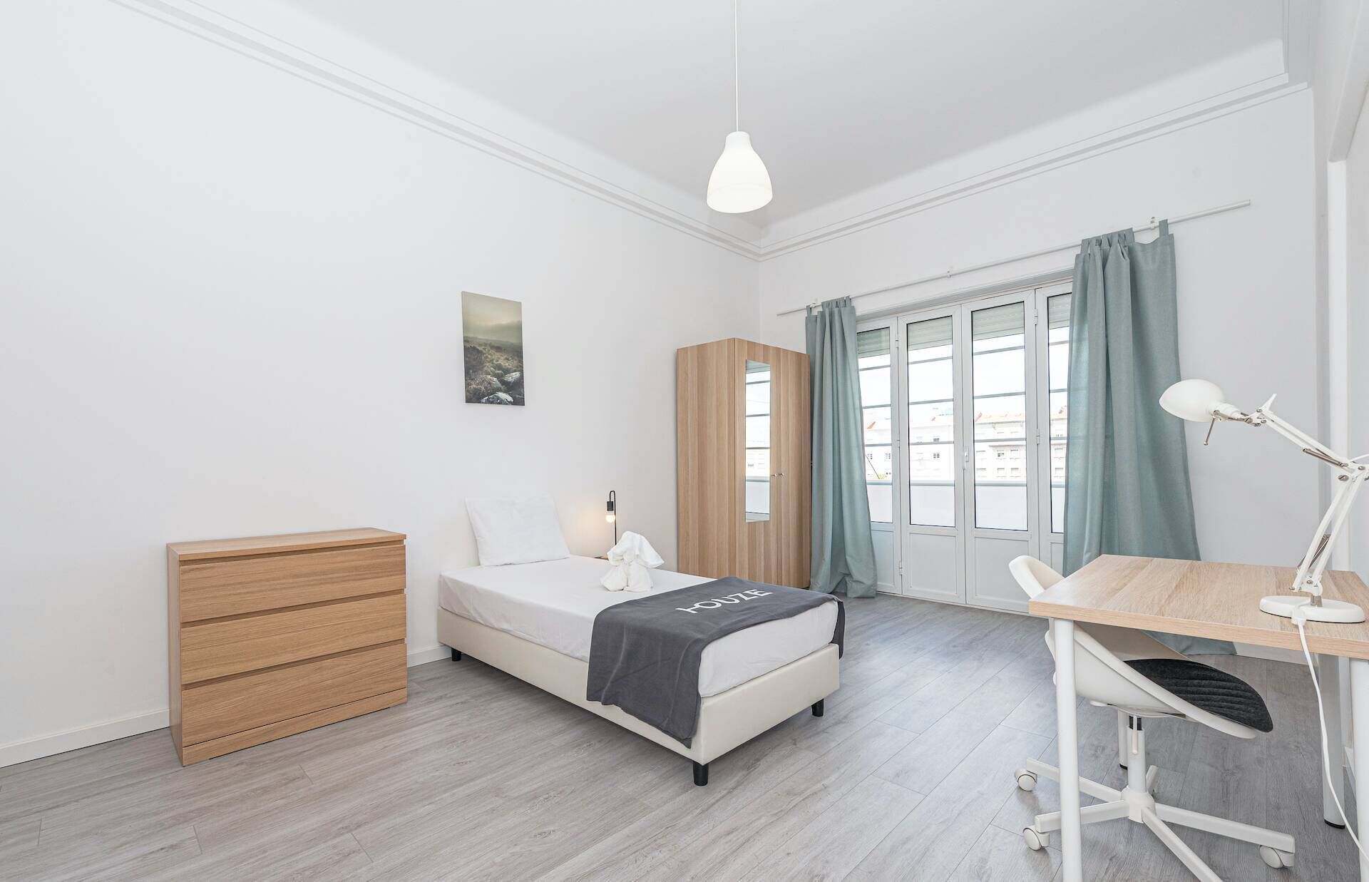 Une chambre moderne comprenant un lit, une table de chevet, une armoire, un bureau avec une chaise et une fenêtre avec des rideaux.