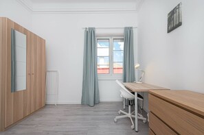 Ein Zimmer mit Schreibtisch, Stuhl und Heizkörper.