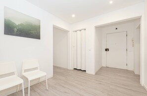A hallway with a painting, two white chairs, a door, and a light switch. - HOUZE City Center spacious 9 rooms flat, best view (Lisboa)