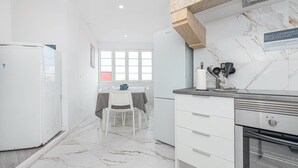 Una cucina moderna con mobili bianchi, una schiena di marmo e un forno integrato.