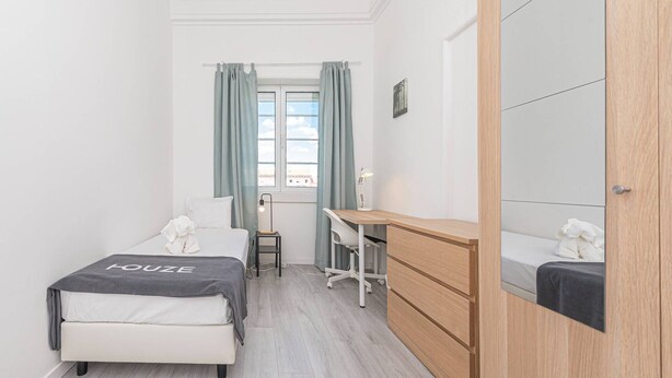 Una camera compatta con un letto, una scrivania e un armadio.