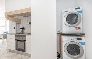 A modern kitchen with a built-in oven, a countertop with kitchen utensils, and a washing machine stacked on top of another appliance. - HOUZE City Center spacious 9 rooms flat, best view (Lisboa)