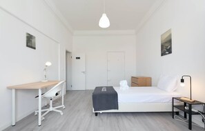 A minimalist hotel room with a bed, bedside table, desk, and chair. - HOUZE City Center spacious 9 rooms flat, best view (Lisboa)