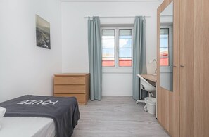 A bedroom with a bed, a wooden dresser, a desk with a chair, a window with curtains, and a mirror. - HOUZE City Center spacious 9 rooms flat, best view (Lisboa)