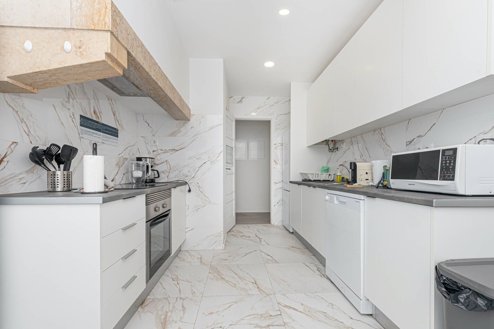 A modern kitchen with white cabinets, a built-in oven, a microwave, and a coffee maker.