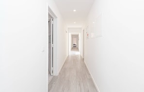 A corridor with white walls and a wooden floor, leading to a bedroom with a bed and a nightstand. - HOUZE City Center spacious 9 rooms flat, best view (Lisboa)