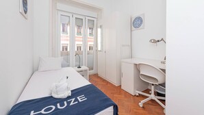 Ein Hotelzimmer mit einem Bett, einem Schreibtisch, einem Stuhl, einem Spiegel und einem Fenster mit Blick auf Gebäude.