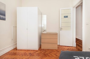 A room with a wardrobe, a mirror, a dresser, and a door with a number plate. - HOUZE Apartment in Historical Lisbon (Lisboa)