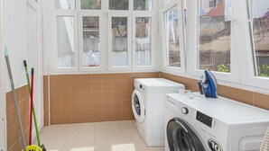 Ein Waschraum mit Waschmaschine, Trockner und einem Fenster mit Blick ins Freie.