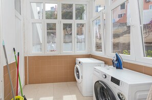A laundry room with a washing machine, a dryer, and a window with a view of the outside. - HOUZE Apartment in Historical Lisbon (Lisboa)