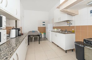 Cozinha compacta com armários brancos, bancada de granito, forno embutido e um pequeno espaço de jantar.