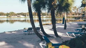 A beach with palm trees, a lake, and lounge chairs. - Family Escape at Holiday Inn Club Vacations Orange Lake (Kissimmee)
