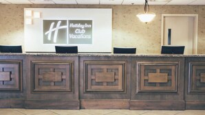 En receptionsdisk med en stor skærm, der viser "Holiday Inn Club Vacations", og en moderne lampe over disken.