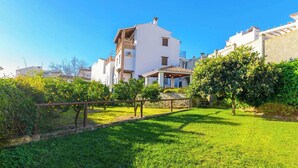 A residential area with white buildings, a grassy lawn, and a lemon tree. - Huerta San Francisco Casarabonela by Ruralidays (Málaga)