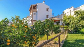 A residential area with a white building, a garden with orange trees, and a clear blue sky. - Huerta San Francisco Casarabonela by Ruralidays (Málaga)