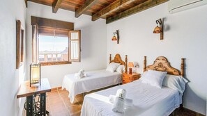 A hotel room with two single beds, a wooden headboard, a small table with a lamp, and a window with a view. - Huerta San Francisco Casarabonela by Ruralidays (Málaga)