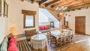 Ein gemütliches Interieur mit Essbereich, einer Treppe und einer Sitzecke mit bunten Kissen.