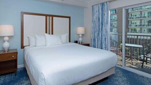 A hotel room with a large bed, two bedside tables with lamps, a view of a balcony with a railing, and a window with curtains. - Oceanfront 2BR Deluxe at Club Wyndham Oceanside Pier Resort in California (Oceanside)