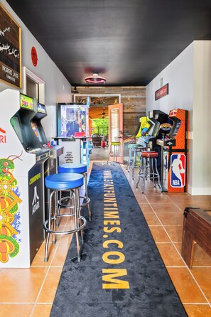 Ein Flur mit Spielautomaten, einem Tischtennisplatte und einem schwarzen Teppich mit dem Aufdruck 'FUN TIMES.COM'.
