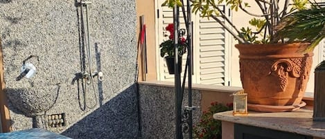 A pool area with a stone wall, a potted plant, and a terracotta pot.